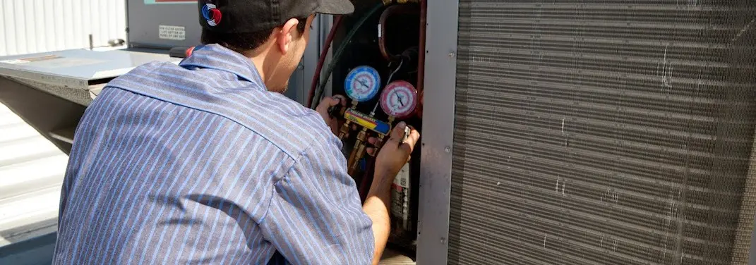 HVAC technician servicing a condenser unit in Sherwood